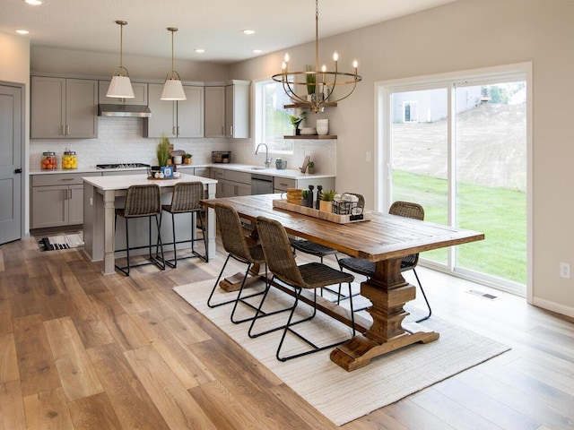 dining room with an inviting chandelier, light wood-type flooring, and a wealth of natural light