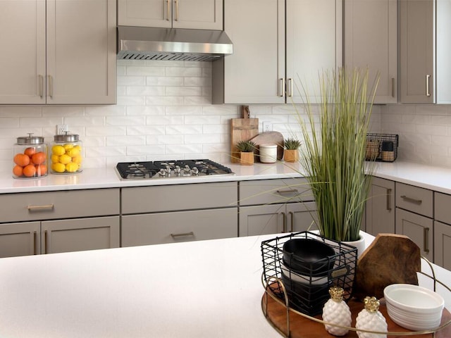 kitchen with gray cabinets, ventilation hood, decorative backsplash, and stainless steel gas cooktop