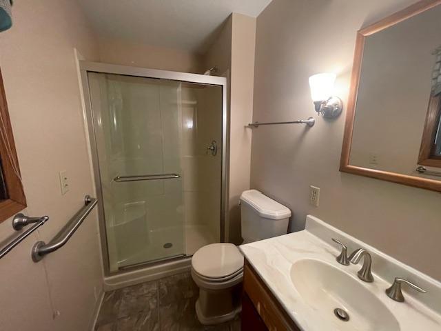 bathroom featuring vanity, walk in shower, and toilet