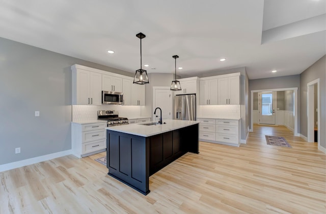 kitchen with sink, backsplash, hanging light fixtures, a kitchen island with sink, and stainless steel appliances