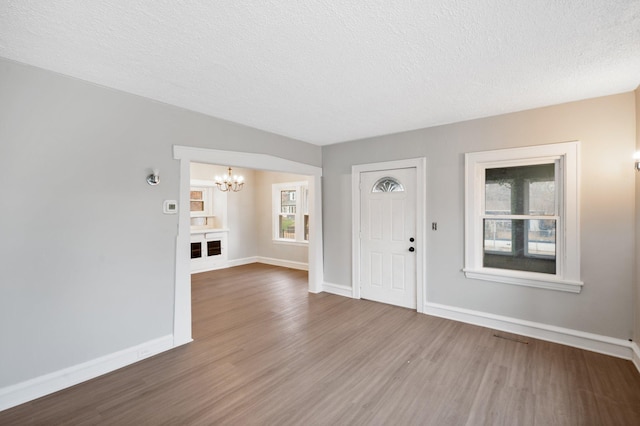 foyer entrance with a fireplace, a chandelier, hardwood / wood-style floors, and a textured ceiling