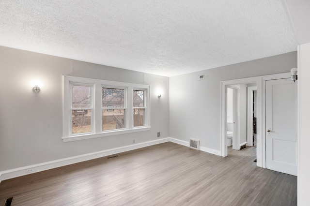 unfurnished room featuring light hardwood / wood-style floors and a textured ceiling