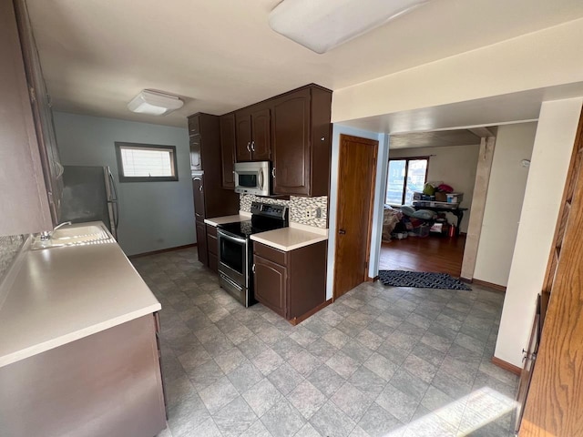 kitchen with tasteful backsplash, dark brown cabinetry, stainless steel appliances, and sink