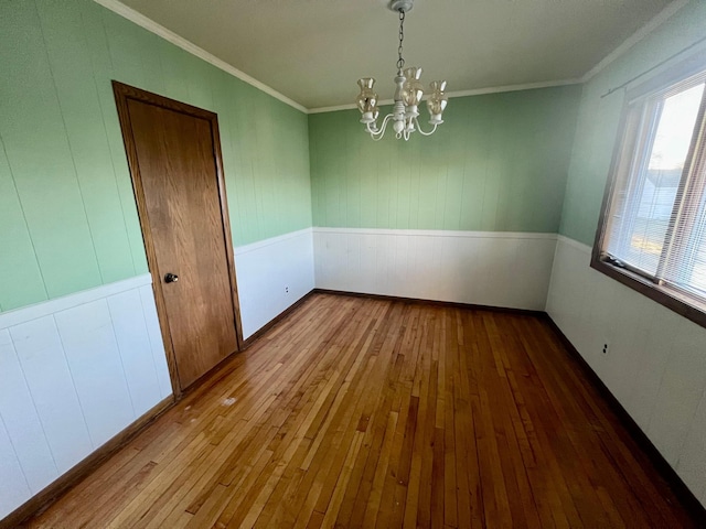 spare room featuring ornamental molding, a notable chandelier, and light hardwood / wood-style floors