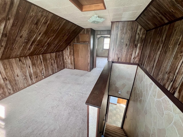 additional living space featuring wooden walls, vaulted ceiling, and light carpet