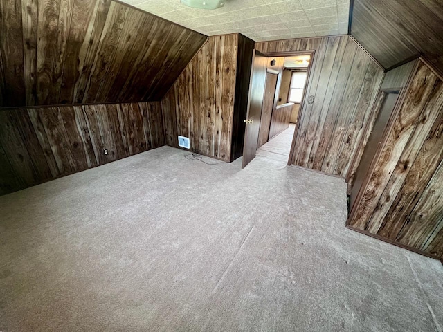 additional living space featuring lofted ceiling, wooden walls, and light colored carpet