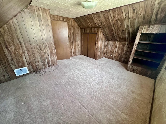 additional living space with vaulted ceiling, wooden walls, and carpet floors