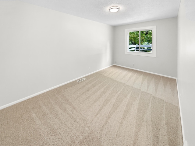 carpeted empty room featuring a textured ceiling