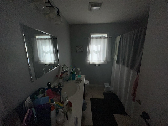 bathroom featuring tile patterned flooring, vanity, walk in shower, and toilet