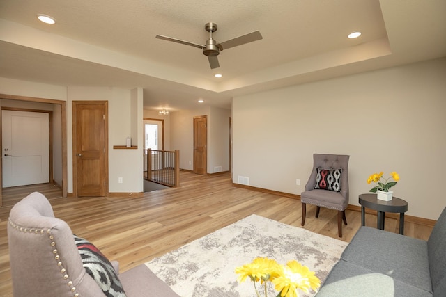 sitting room featuring ceiling fan, a raised ceiling, and hardwood / wood-style floors