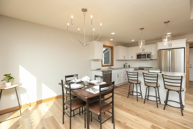 dining area featuring light hardwood / wood-style floors, a chandelier, and sink