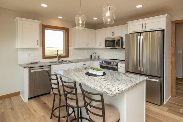 kitchen with a kitchen island, white cabinetry, sink, and stainless steel appliances