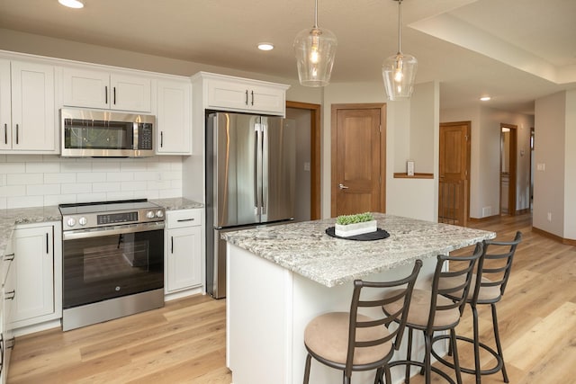 1309 18th St NE, Austin, MN 55912 - kitchen with white cabinets, light wood-style floors, light stone countertops, and appliances with stainless steel finishes