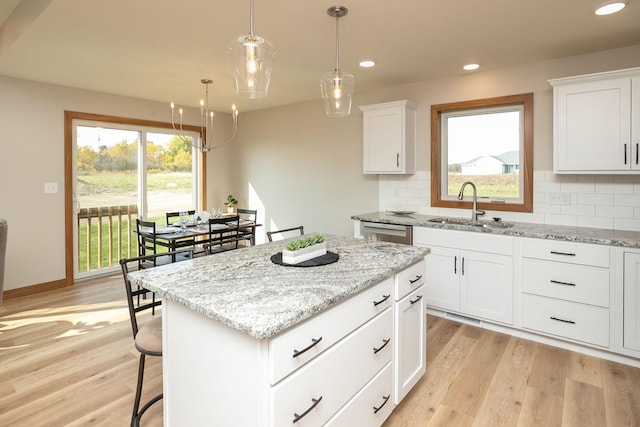 kitchen with a kitchen island, light hardwood / wood-style flooring, sink, decorative backsplash, and white cabinets