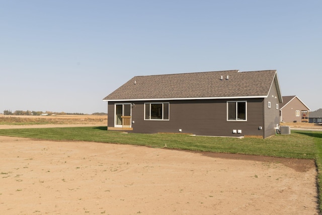 rear view of house featuring central AC unit and a lawn