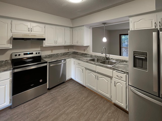 kitchen with stainless steel appliances, sink, pendant lighting, white cabinetry, and a textured ceiling