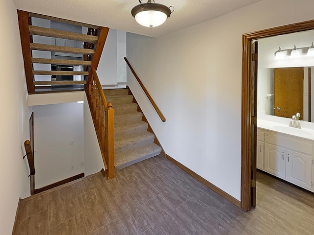 staircase with hardwood / wood-style floors and sink