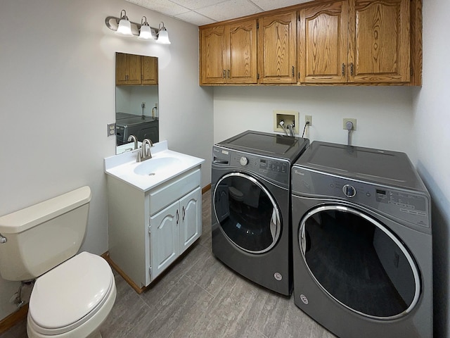 clothes washing area with washing machine and clothes dryer, sink, and hardwood / wood-style flooring