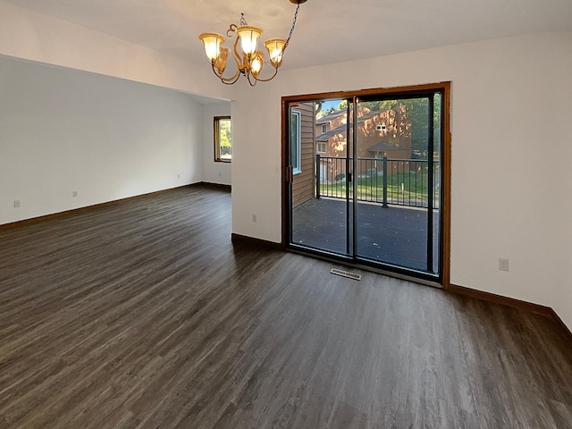 spare room featuring a notable chandelier and dark wood-type flooring