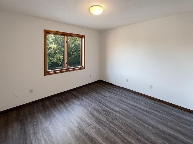 unfurnished room with a textured ceiling and dark hardwood / wood-style floors