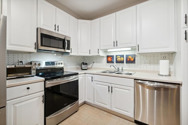 kitchen featuring white cabinetry, backsplash, appliances with stainless steel finishes, and sink