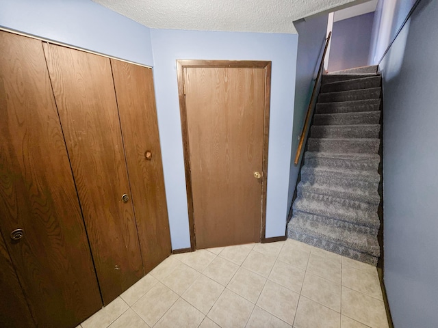 stairway featuring tile patterned floors and a textured ceiling