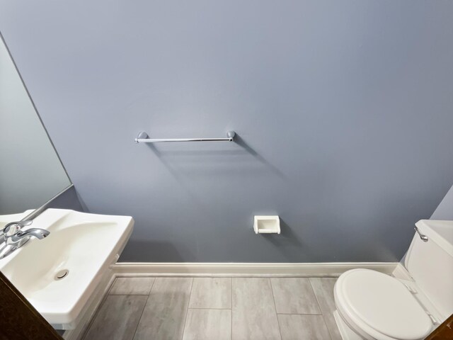 2360 Dorland Pl E, Maplewood, MN 55119 - half bathroom featuring toilet, wood finished floors, a sink, and baseboards