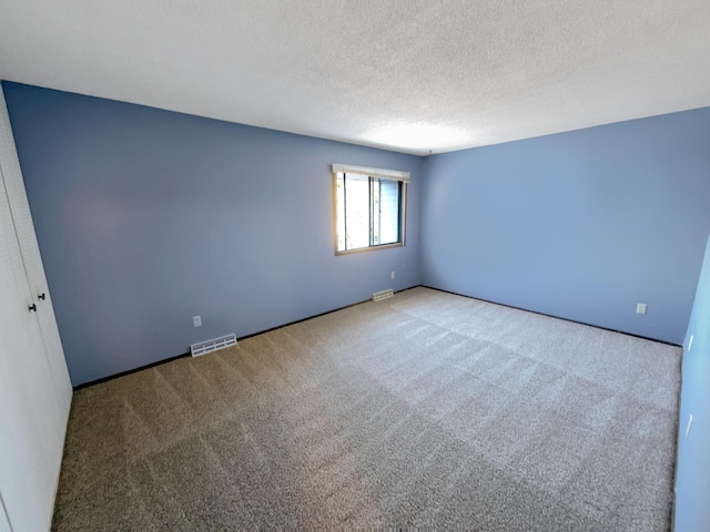 spare room with light carpet and a textured ceiling