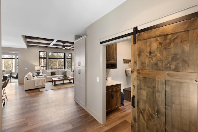 hallway featuring coffered ceiling, dark hardwood / wood-style floors, beam ceiling, and a barn door