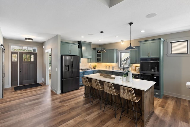 kitchen featuring sink, a breakfast bar area, appliances with stainless steel finishes, a kitchen island, and pendant lighting