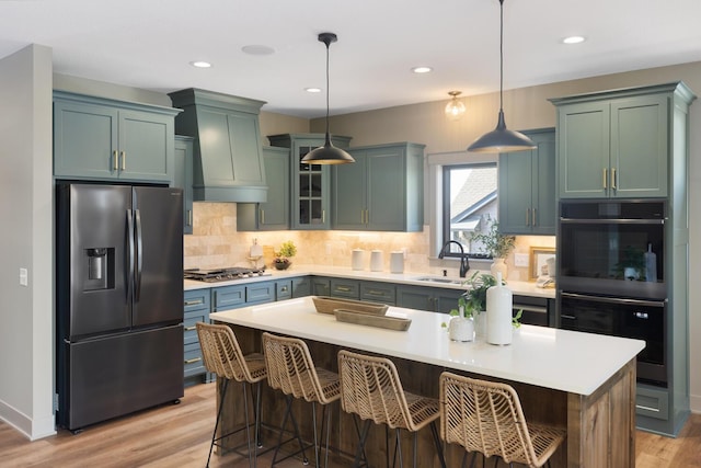 kitchen featuring sink, a breakfast bar area, stainless steel appliances, a kitchen island, and decorative light fixtures