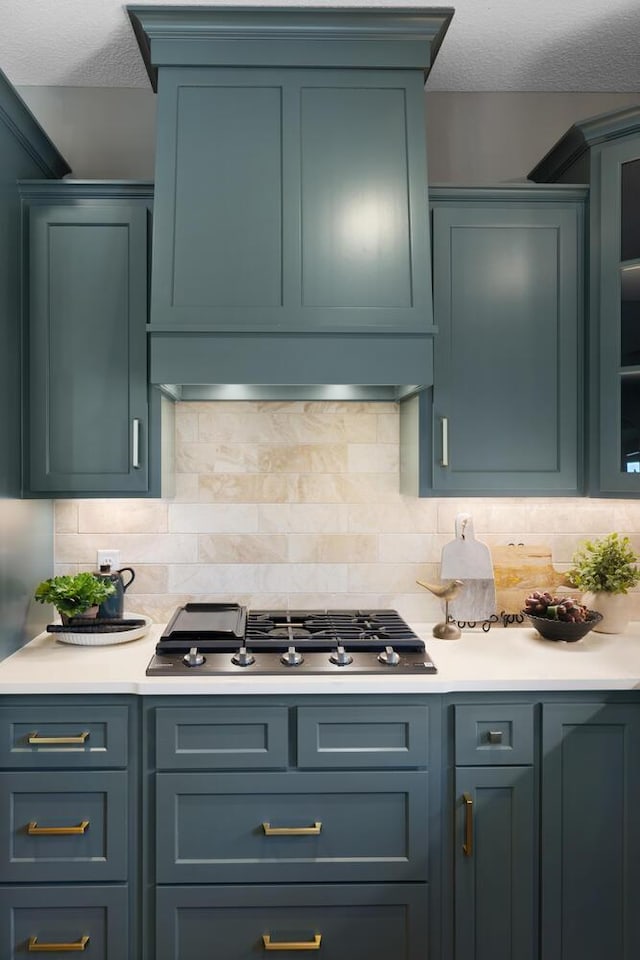 kitchen with tasteful backsplash, stainless steel gas cooktop, and a textured ceiling