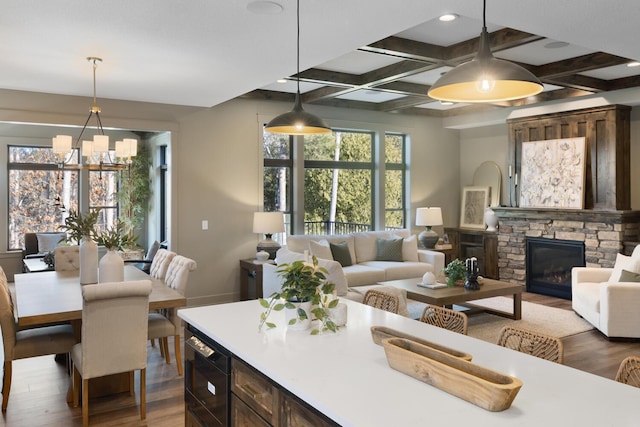 kitchen featuring wood-type flooring, a stone fireplace, coffered ceiling, and pendant lighting