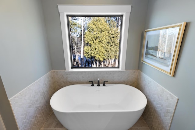 bathroom featuring tile walls and a tub to relax in