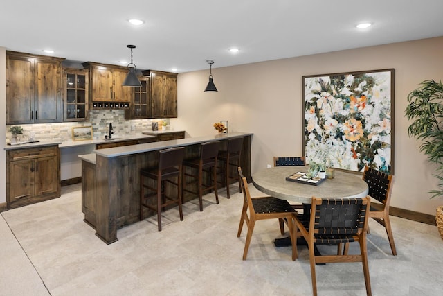 bar with hanging light fixtures, decorative backsplash, and sink