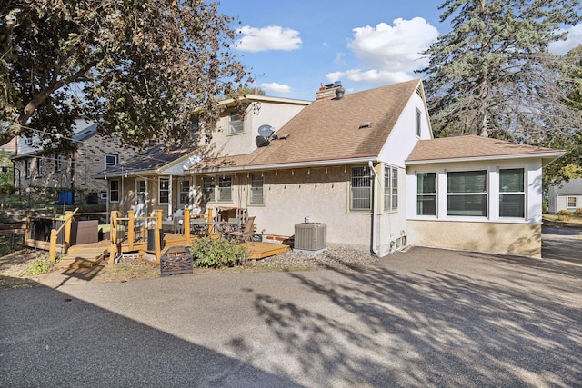 3522 Benjamin St NE, Minneapolis, MN 55418 - back of house with stucco siding, a wooden deck, a chimney, roof with shingles, and central AC unit