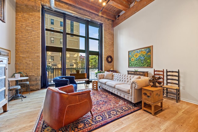 living room featuring brick wall, a high ceiling, beam ceiling, wooden ceiling, and light wood-type flooring