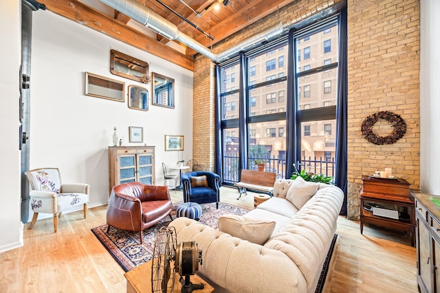 living area featuring a high ceiling, brick wall, wood ceiling, and light hardwood / wood-style flooring