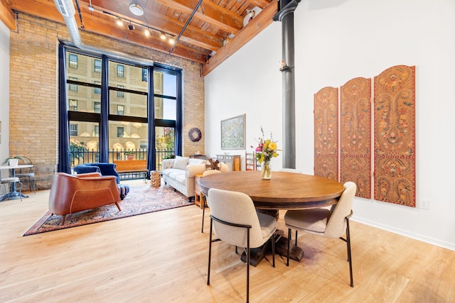 dining area with beamed ceiling, light hardwood / wood-style floors, wood ceiling, and brick wall