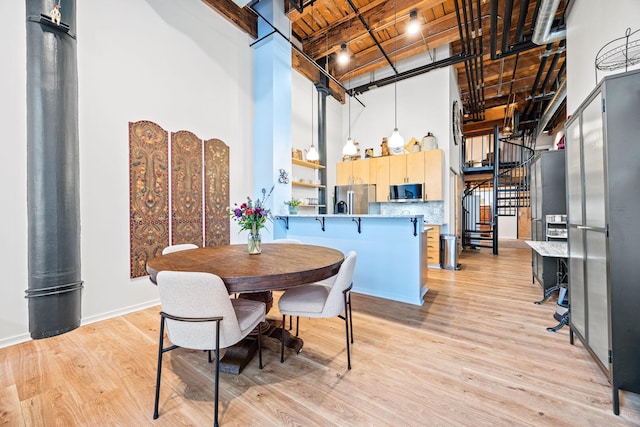 dining area featuring beamed ceiling, light wood-type flooring, wooden ceiling, and a high ceiling