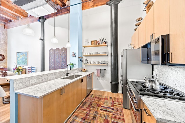 kitchen with sink, light stone countertops, stainless steel appliances, and hanging light fixtures