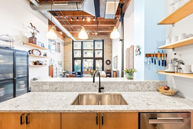 kitchen with light stone countertops, sink, and brick wall