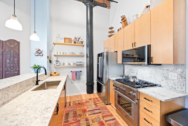 kitchen with pendant lighting, light brown cabinets, sink, light stone counters, and stainless steel appliances