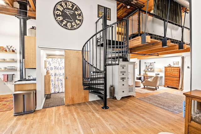 stairway with ornate columns, a high ceiling, and hardwood / wood-style flooring