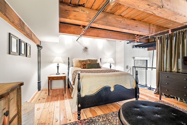 bedroom featuring beamed ceiling and light wood-type flooring