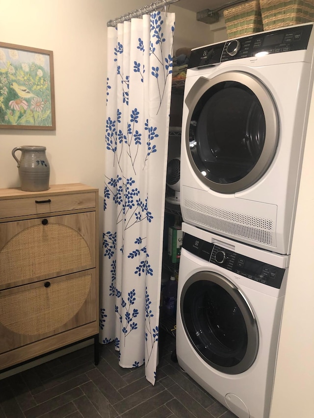 clothes washing area featuring stacked washer and clothes dryer