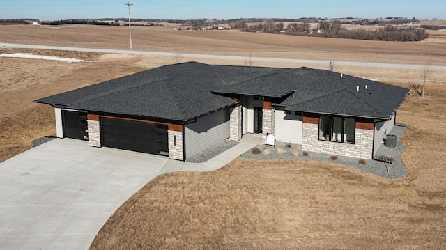 view of front facade featuring a garage, a rural view, central AC unit, and a front lawn