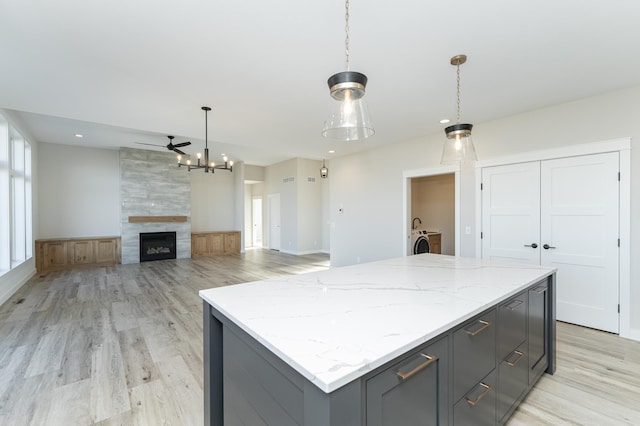 kitchen with light stone countertops, decorative light fixtures, gray cabinets, and a kitchen island