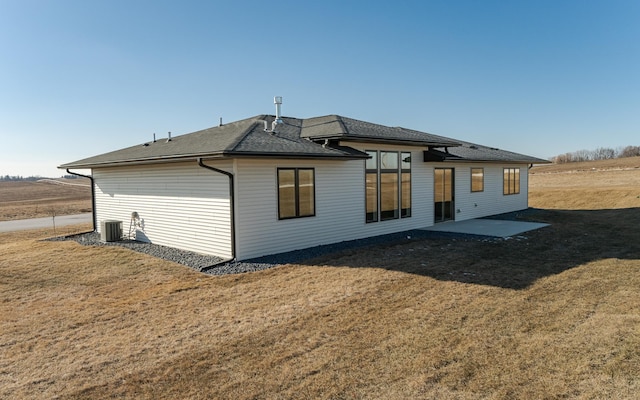 rear view of property featuring central AC and a yard