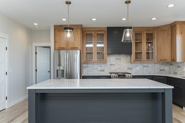 kitchen featuring light stone counters, range, stainless steel fridge with ice dispenser, hanging light fixtures, and a large island